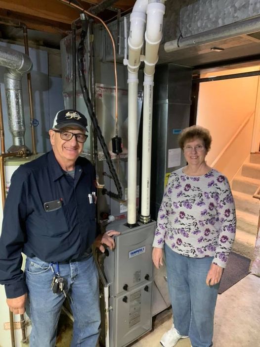 a man and a woman are standing next to a heater in a basement .
