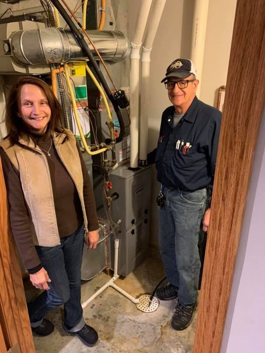 a man and a woman are standing next to a furnace in a basement .
