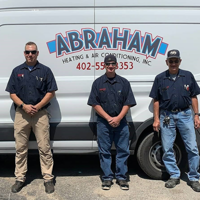 three men are standing in front of an abraham heating and air conditioning van