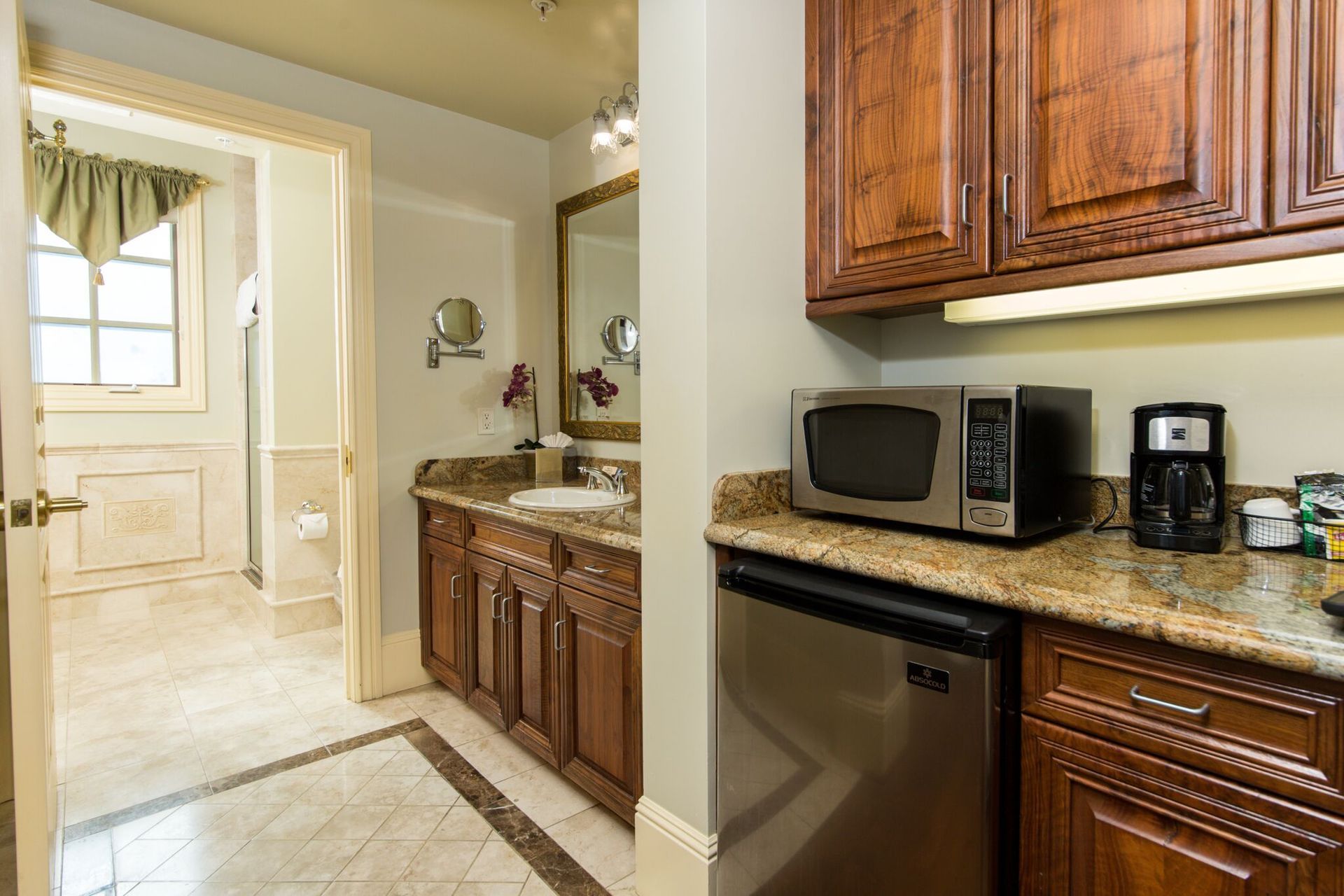 Bathroom with a vanity and a kitchenette area. The kitchenette features a microwave, mini-fridge, and coffee maker.
