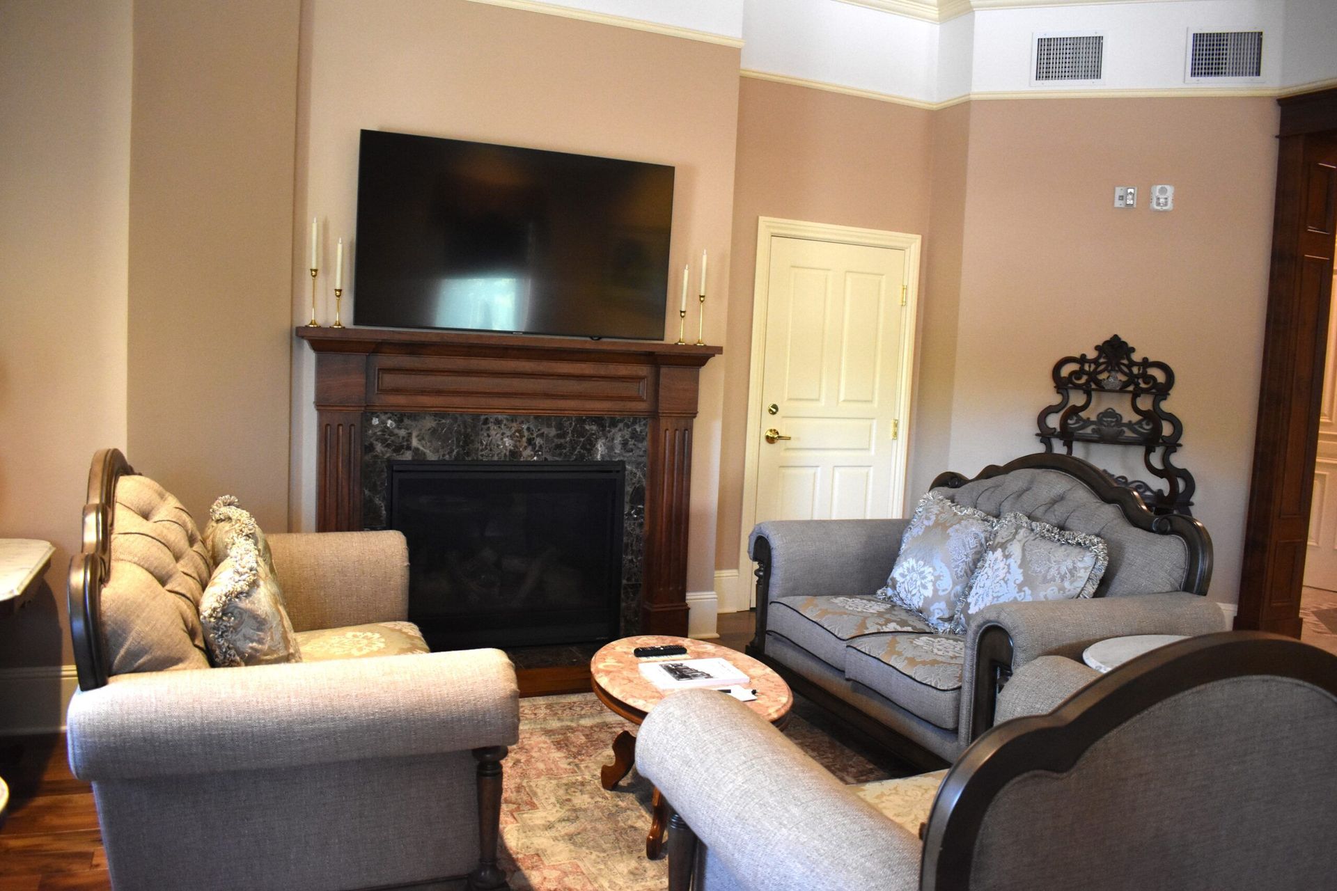 Living room with fireplace and two ornate sofas. A TV  , and a small round table sits in front of the sofas.