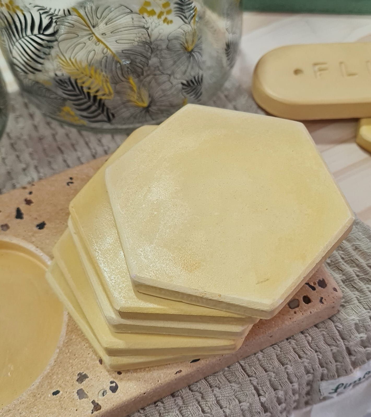 Cuatro posavasos hexagonales de color rosa apilados sobre una tela rayada.