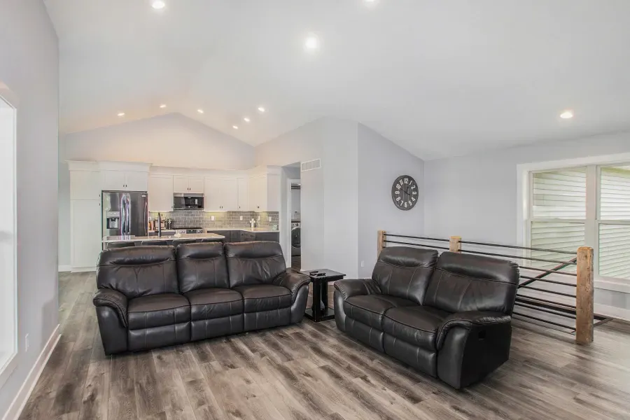 A living room with two couches and a clock on the wall.
