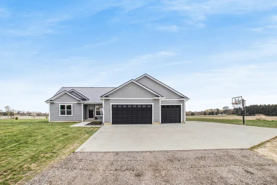 A house with two garages and a basketball hoop in front of it.