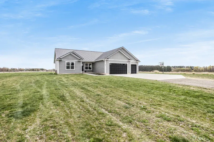 A house is sitting on top of a lush green field.