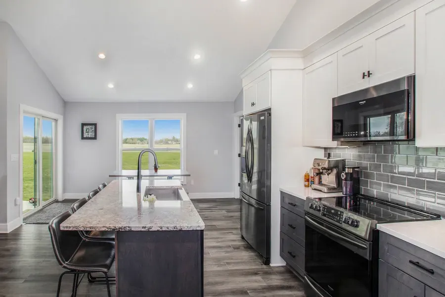 A kitchen with a large island , stove , refrigerator and microwave.