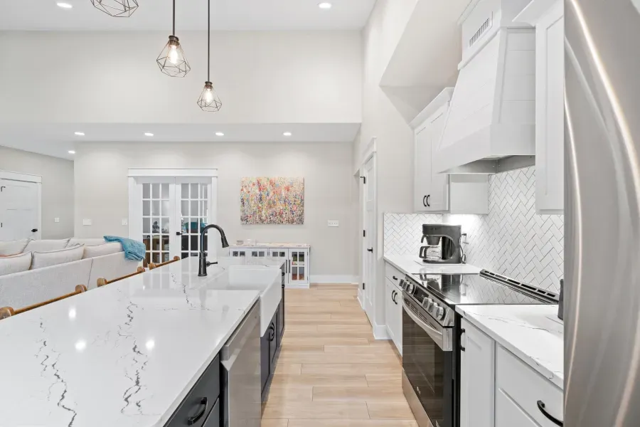 A kitchen with white cabinets , stainless steel appliances , and a large island.