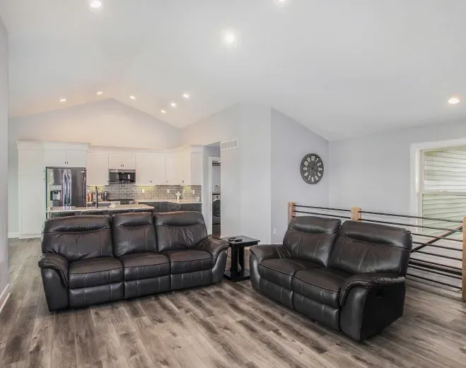 A living room with two couches and a clock on the wall.