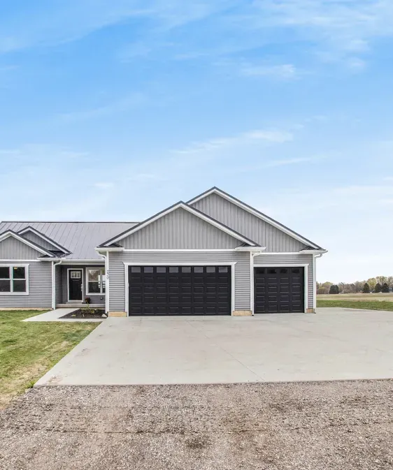 A house with two garage doors and a driveway in front of it.