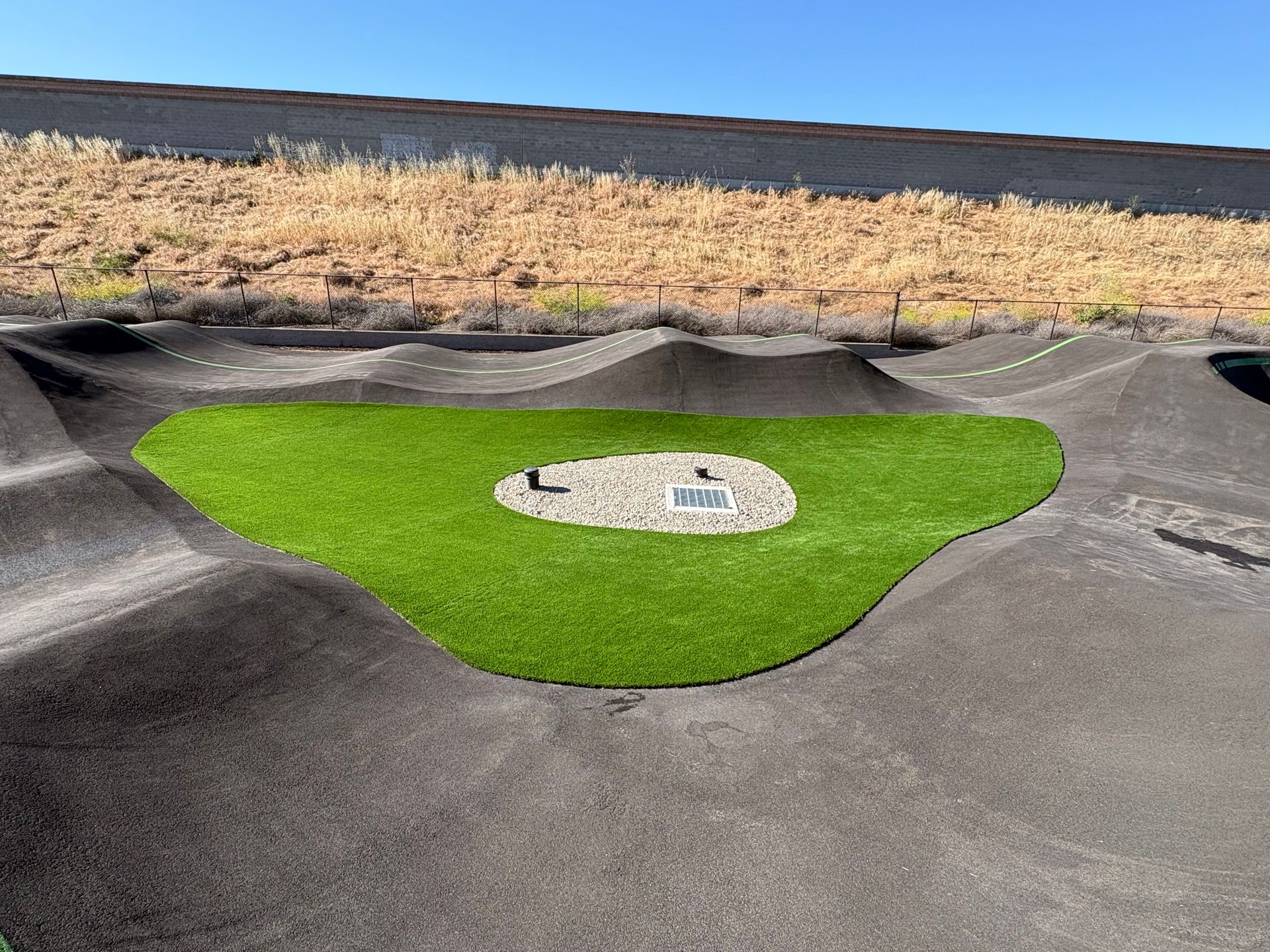 Bright green artificial turf area on a paved mini-golf course with a central hole marker