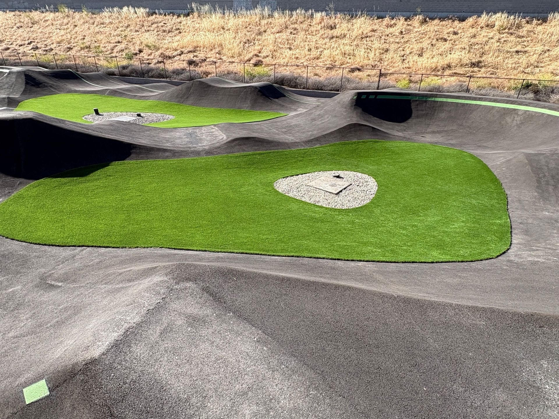 Mini golf course with gray ramps, black tunnels, and bright green putting greens