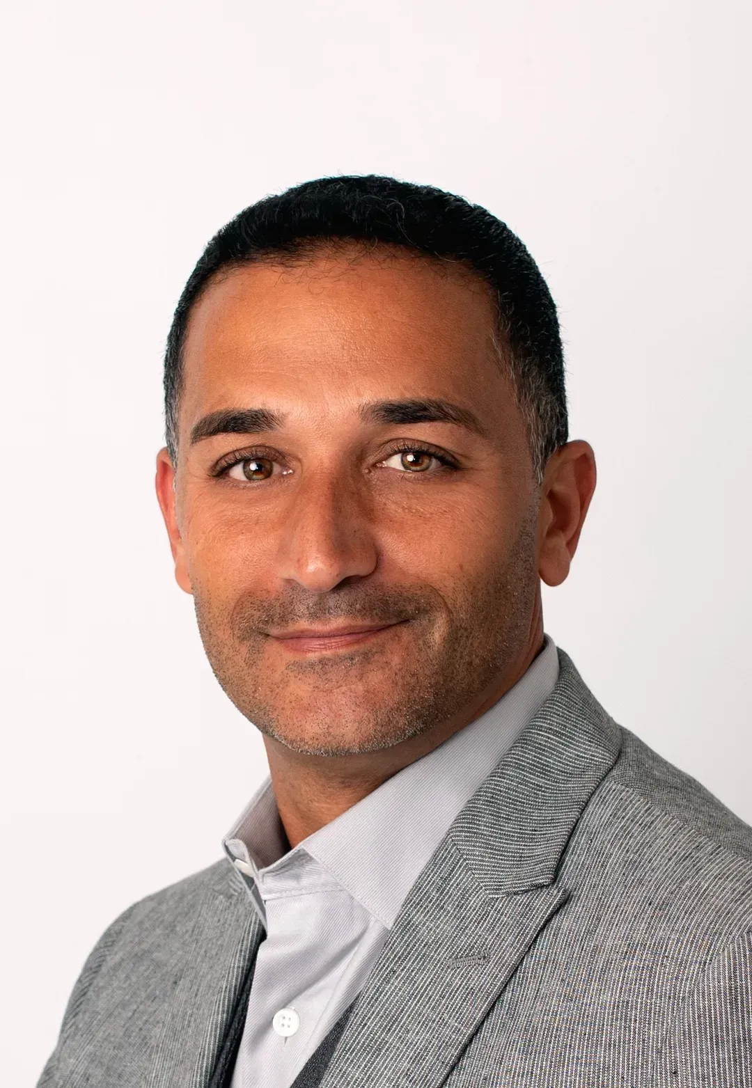 A woman is sitting at a desk with a laptop and a vase of flowers.