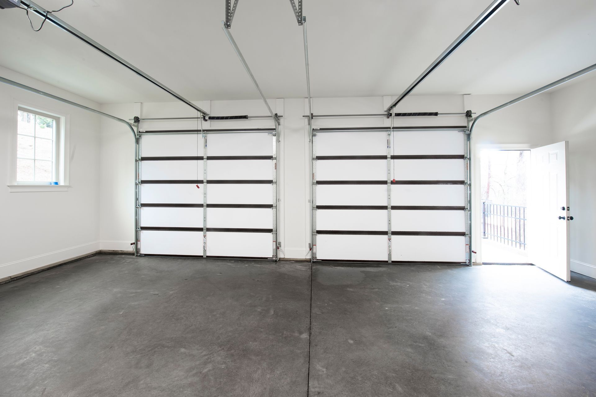 An empty garage with two garage doors open