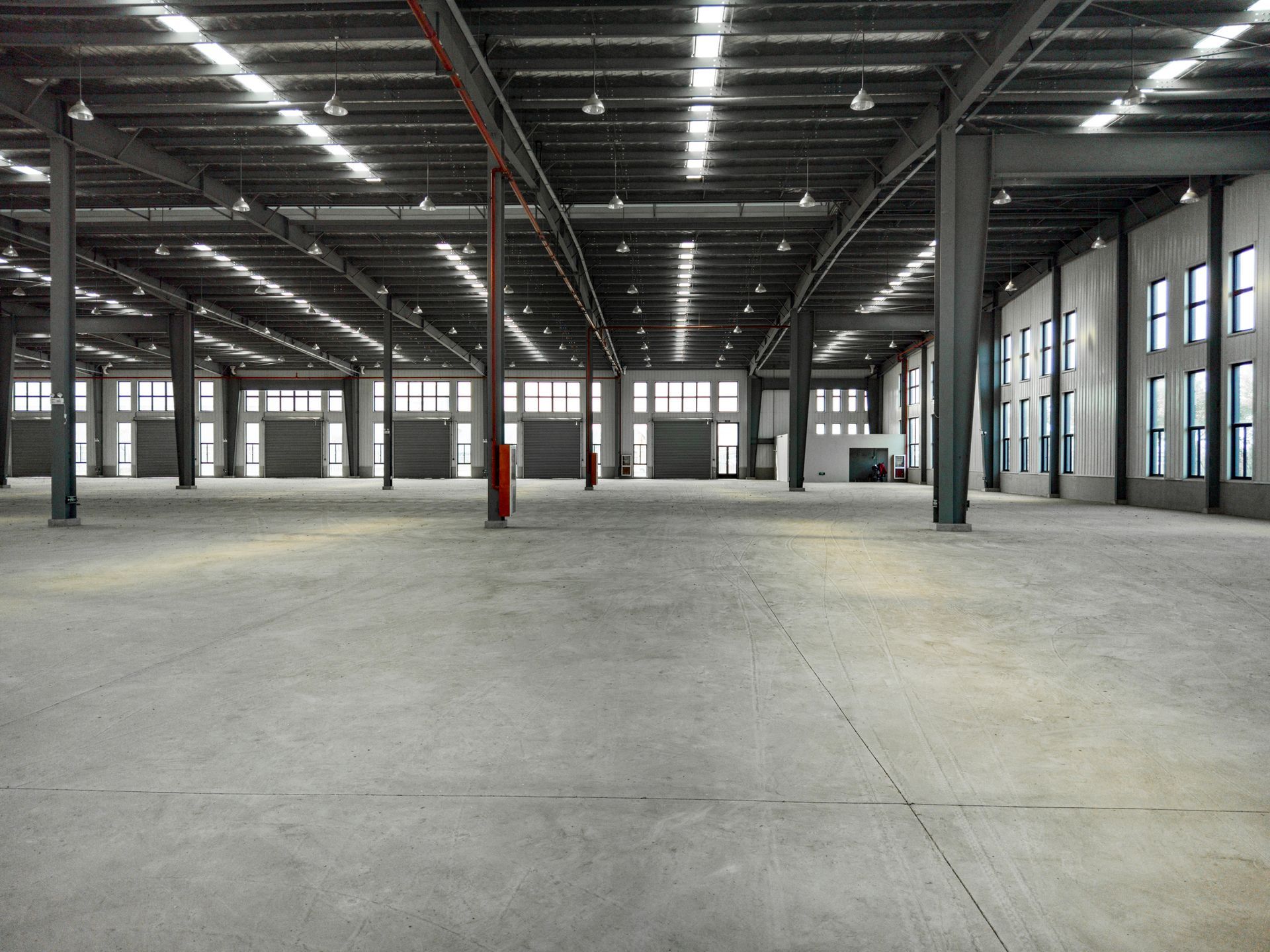 A large empty warehouse with a lot of windows and doors.