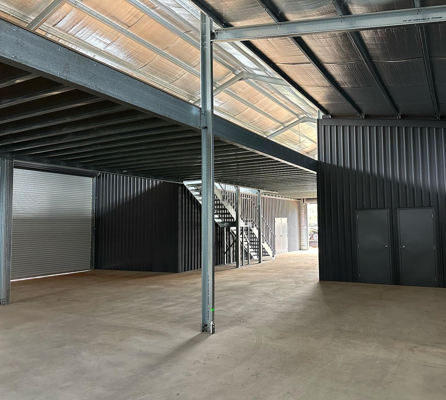 A Modern Grey Building Behind a Black Horizontal Fenced Yard Next to A Road — Complete Sheds In Marulan, NSW