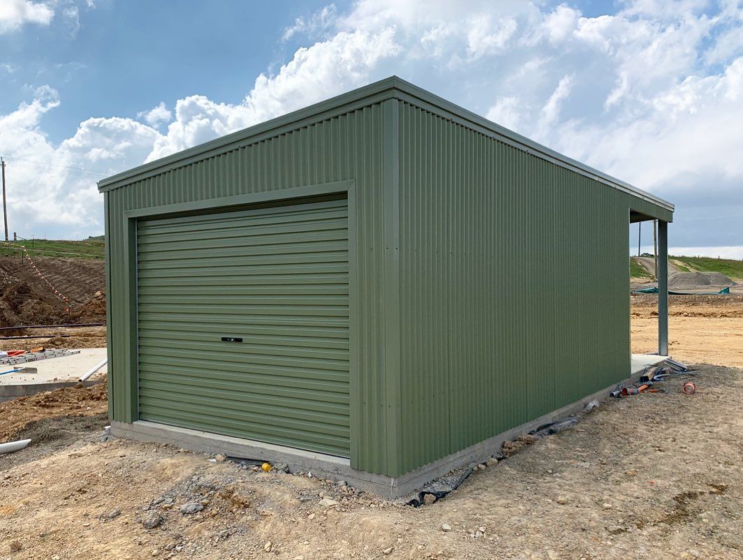 Green Metal Garage with A Roll-Up Door on A Concrete Foundation — Complete Sheds In Marulan, NSW