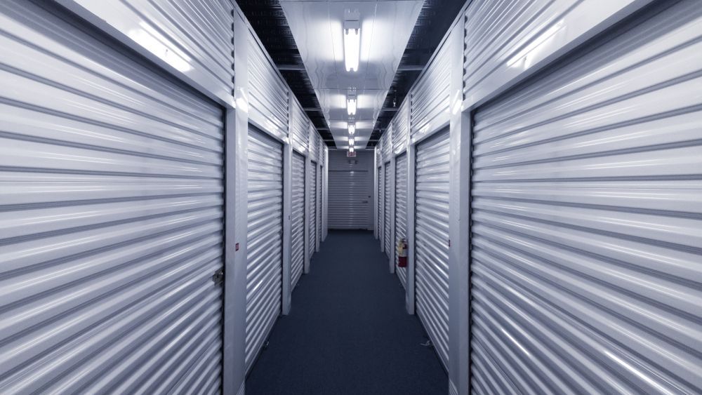 Hallway of Self-Storage Units with Closed, Corrugated Metal Doors, Lit by Overhead Lights — Complete Sheds In Goulburn, NSW