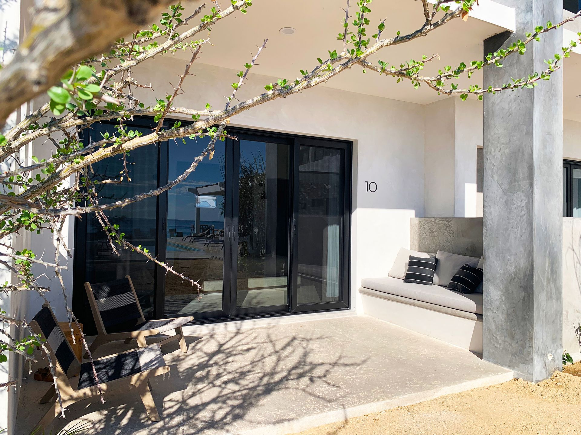 Outdoor patio with sliding glass doors, bench seating, and two striped chairs.