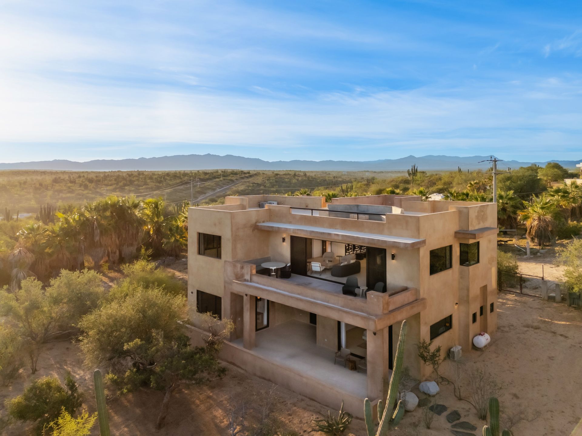 Tan stucco house with balconies overlooking a desert landscape under a blue sky.