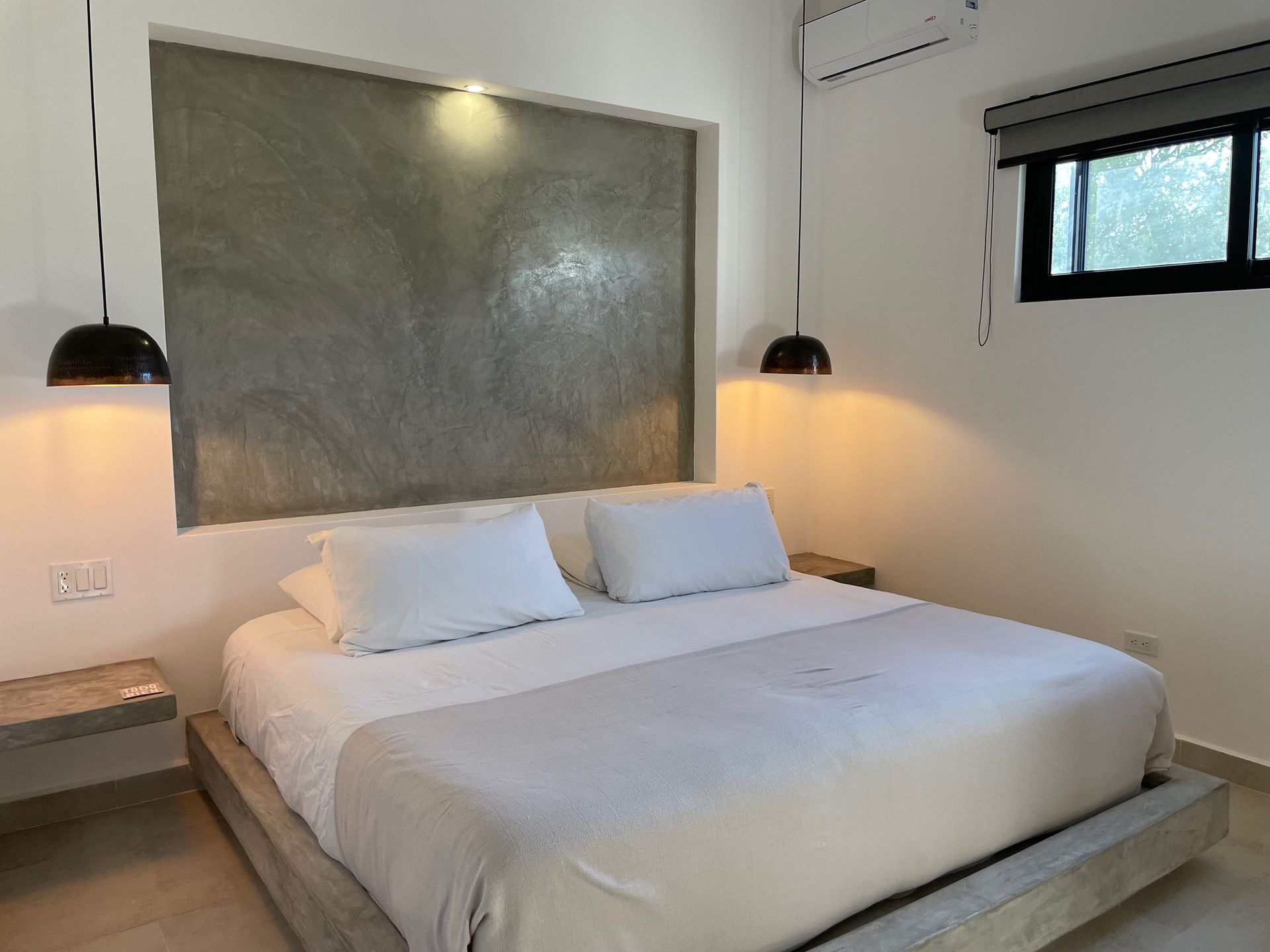 Bedroom with a bed, nightstands, decorative lights, and a small window.