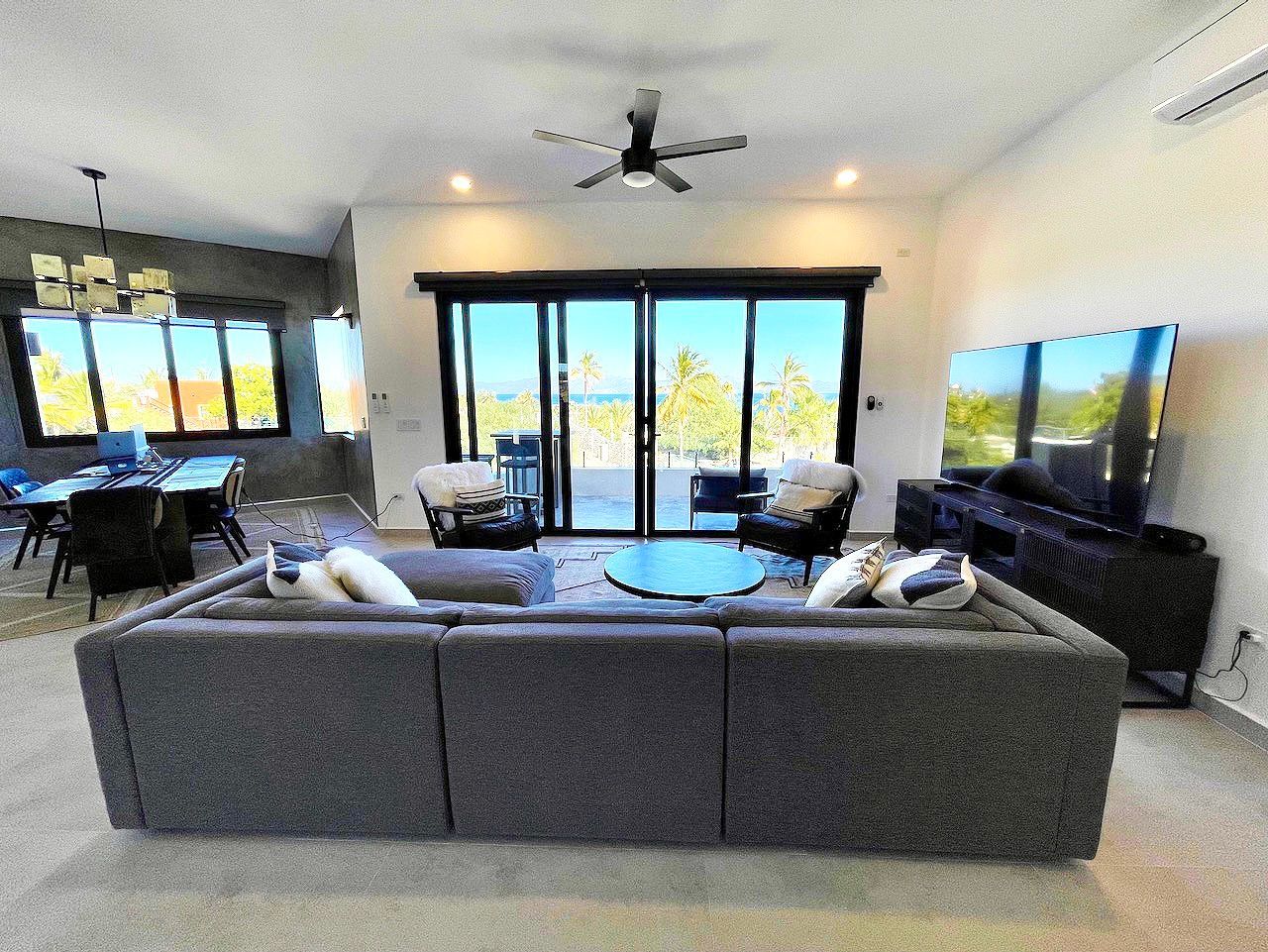Living room with large gray sofa, glass doors, and TV.