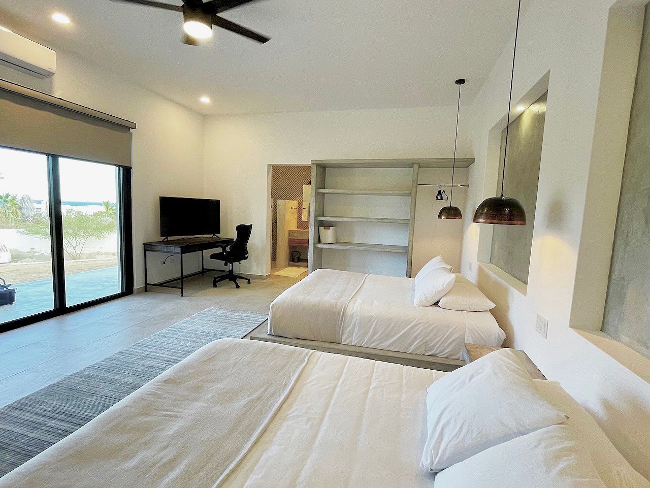 Spacious bedroom with two queen beds, desk, and sliding glass doors with a view.