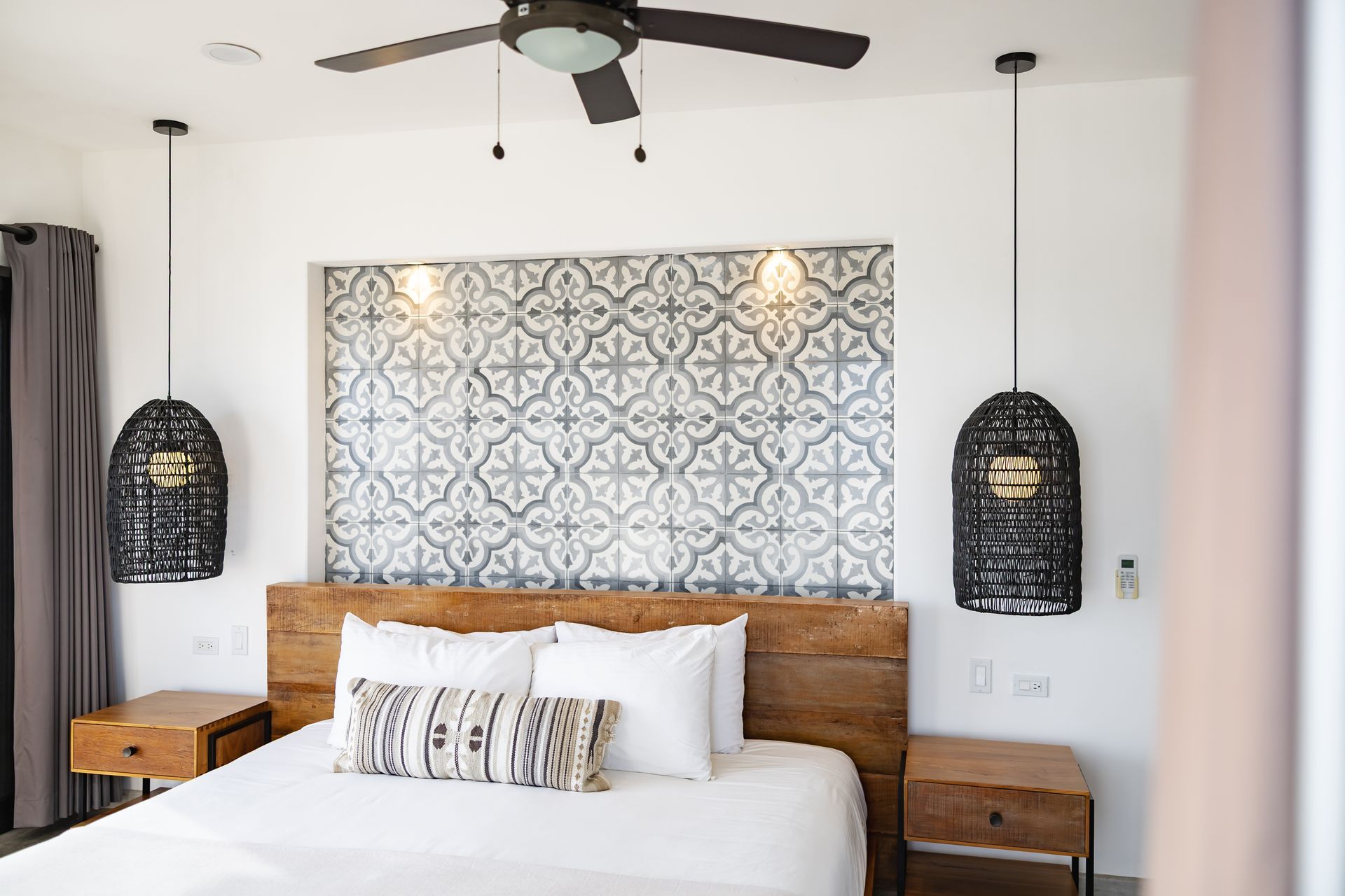 Bedroom with bed, patterned headboard, decorative pendant lights, and nightstands.
