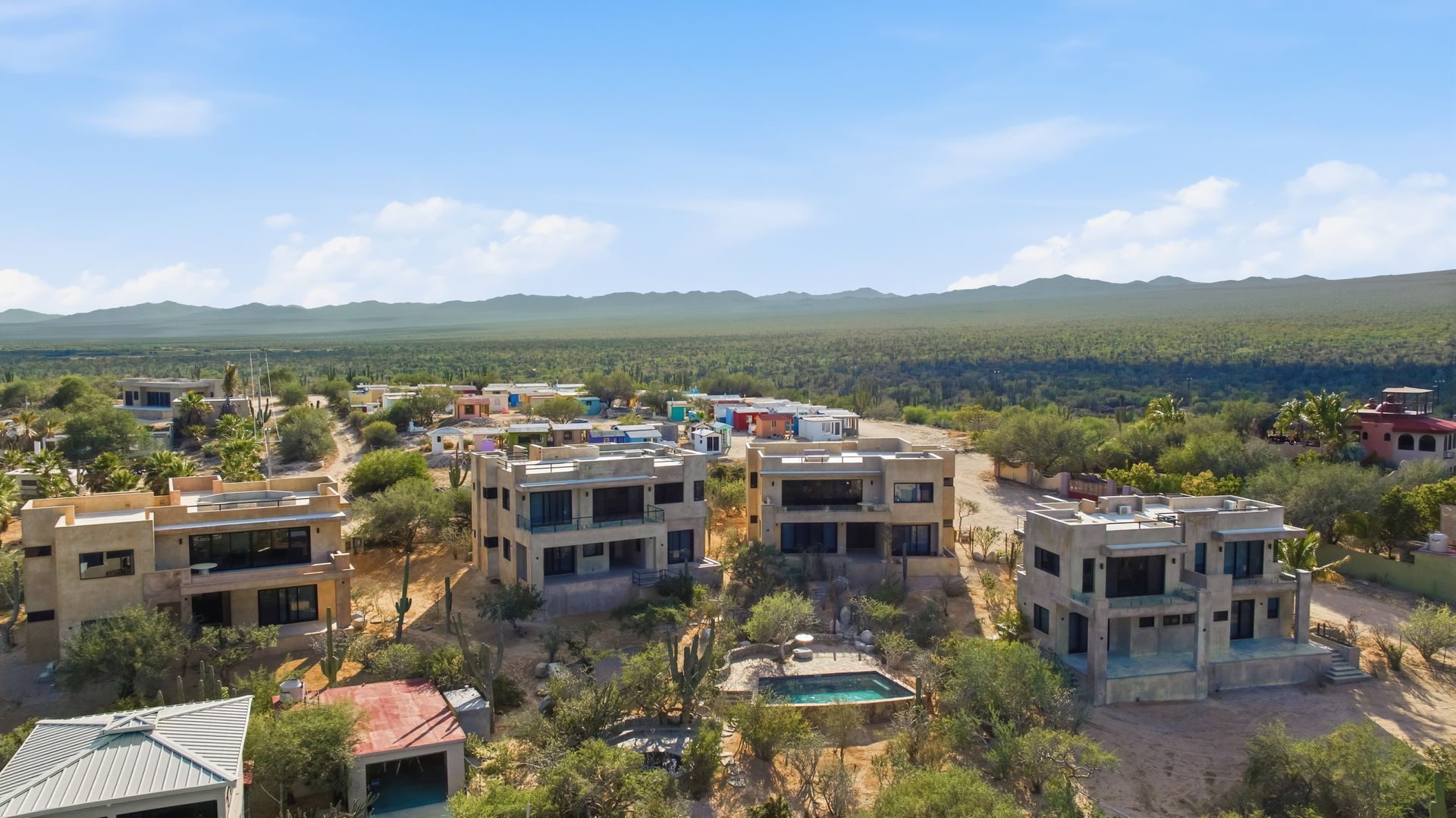 Houses on a hillside with a desert landscape and blue sky.