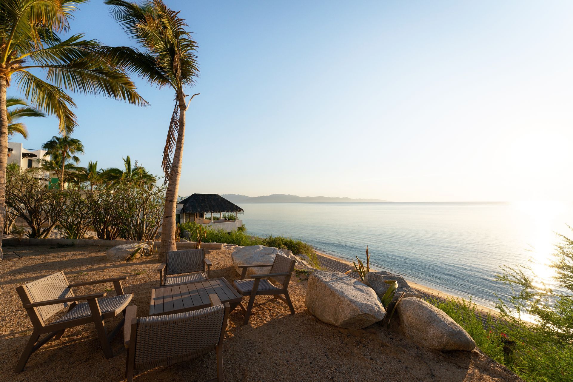 Beachside seating area with ocean view, palm trees, and a small cabana.