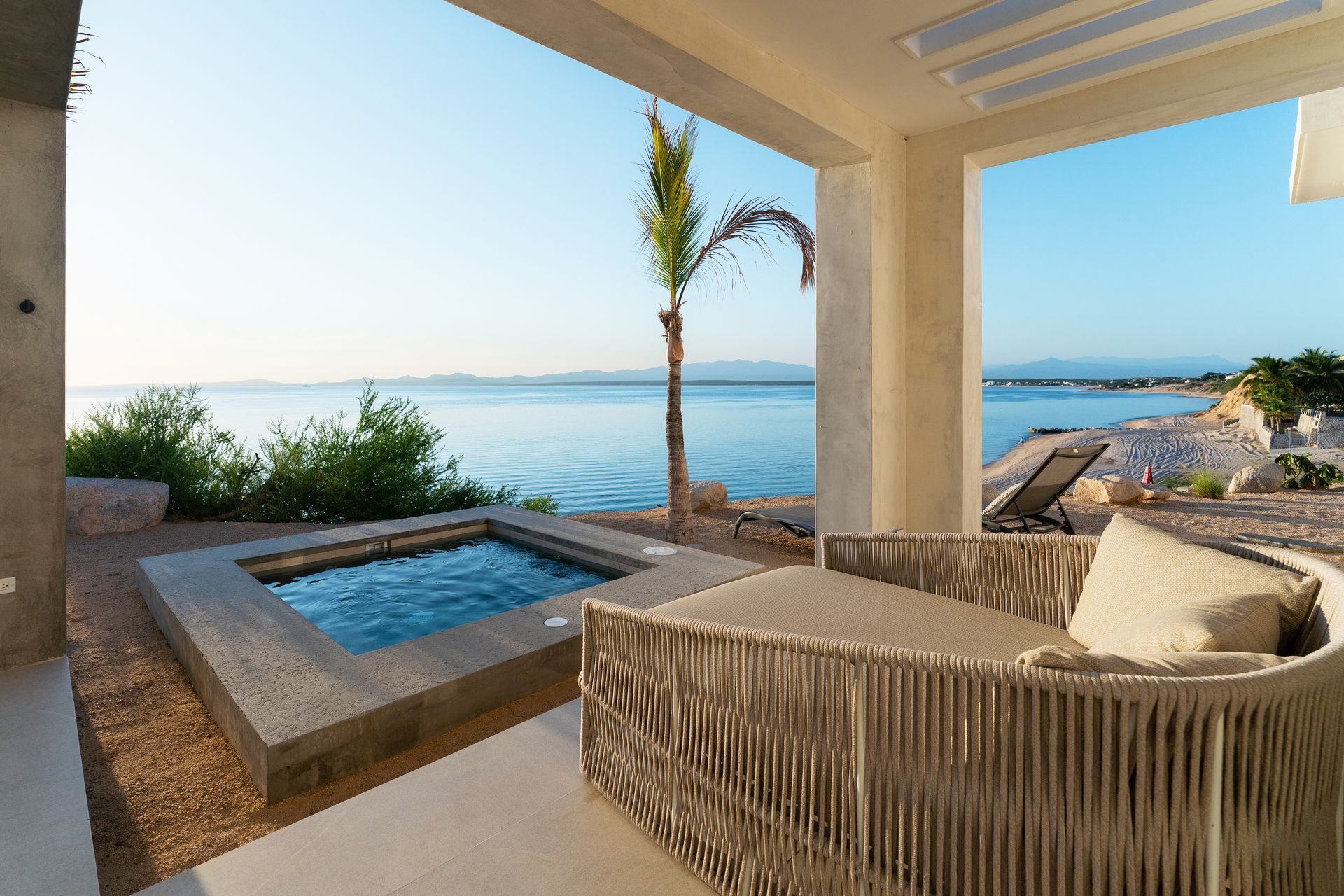 Outdoor patio with a jacuzzi, cushioned seating, and ocean view.