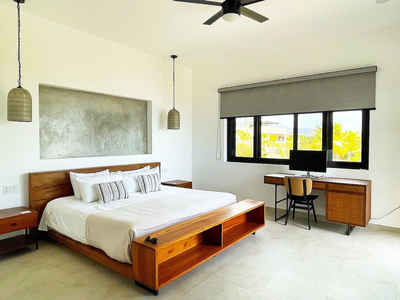 Bedroom with a wooden bed, desk, and gray window shade. Bright natural light.