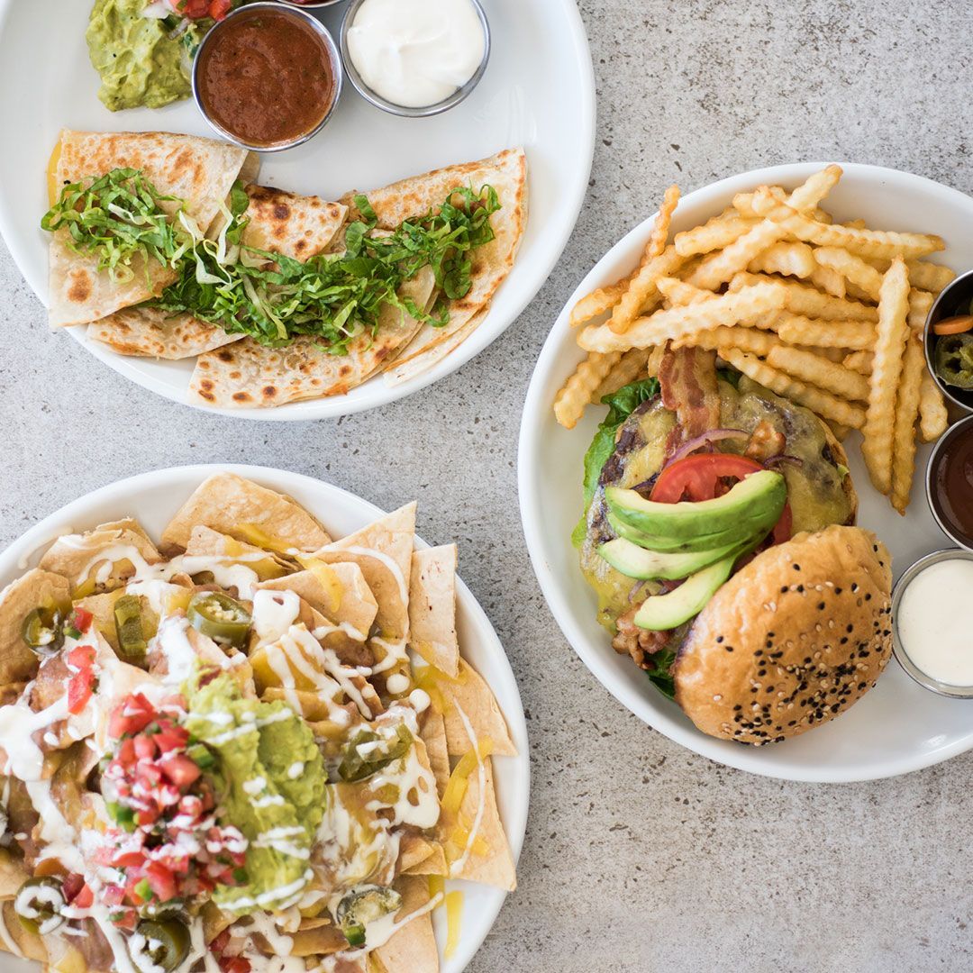Plates of food: quesadilla with toppings, burger with fries, and nachos with various toppings.
