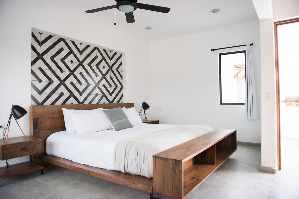 Modern bedroom with geometric headboard, wooden bed frame, and neutral tones.