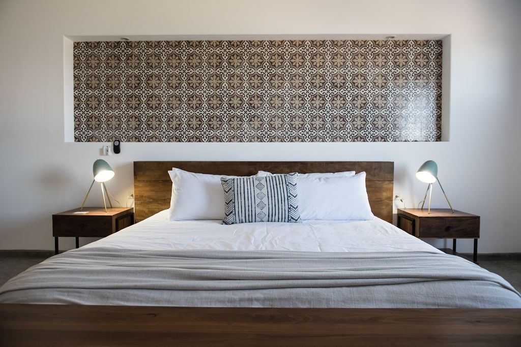 Bedroom with wooden bed, bedside tables, patterned wall niche, and lamps.