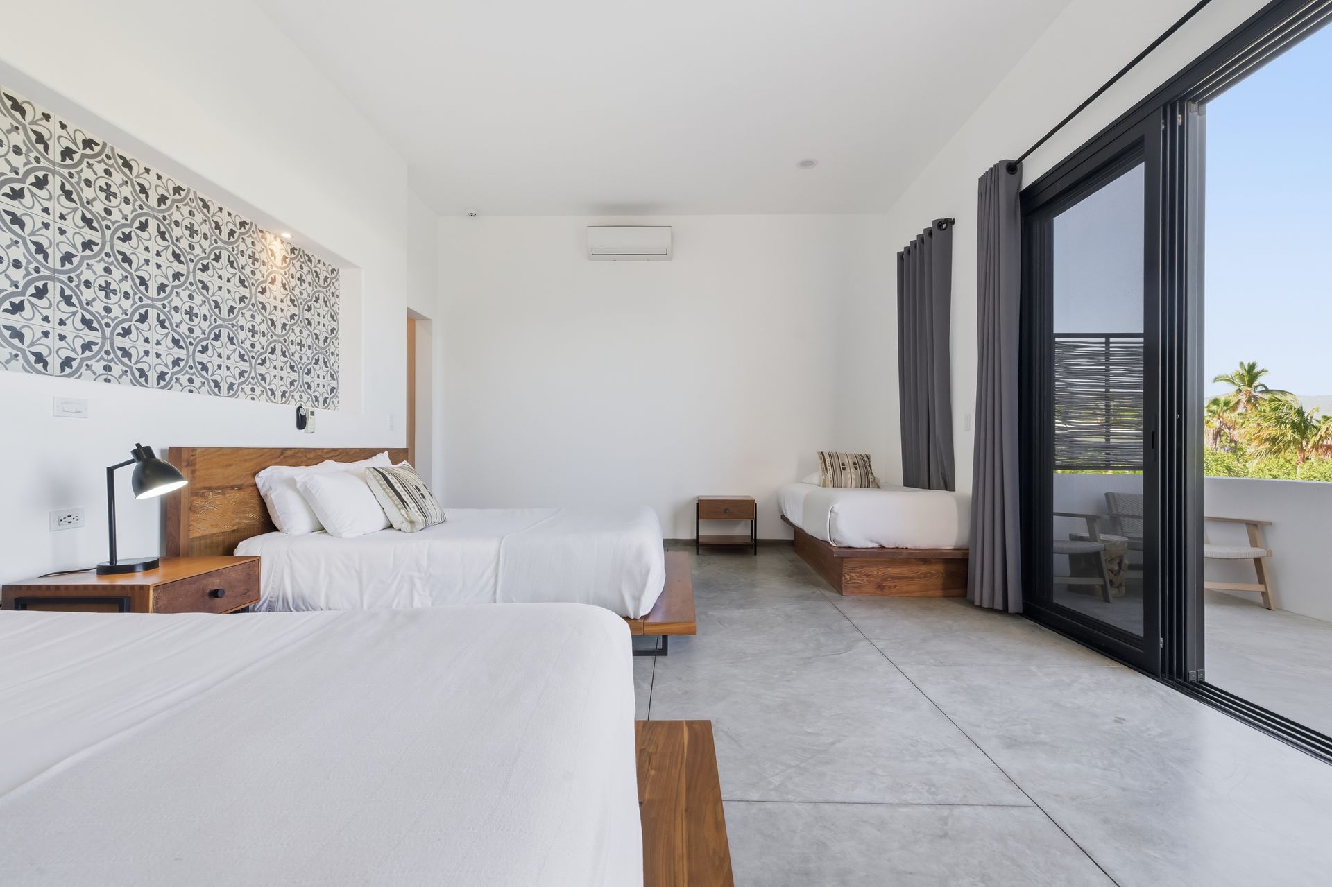 Bedroom with two queen beds, a single bed, and large glass doors leading to a balcony.