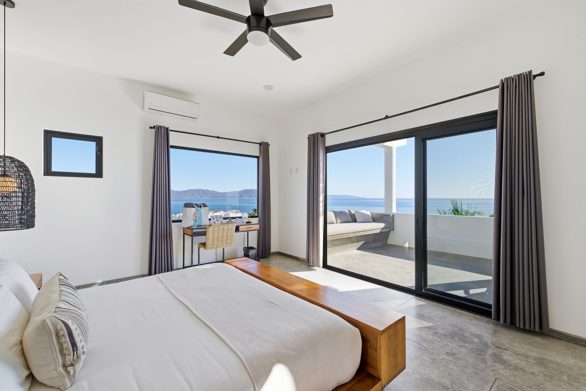 Bedroom with ocean view; bed, desk, and sliding glass doors onto a balcony.