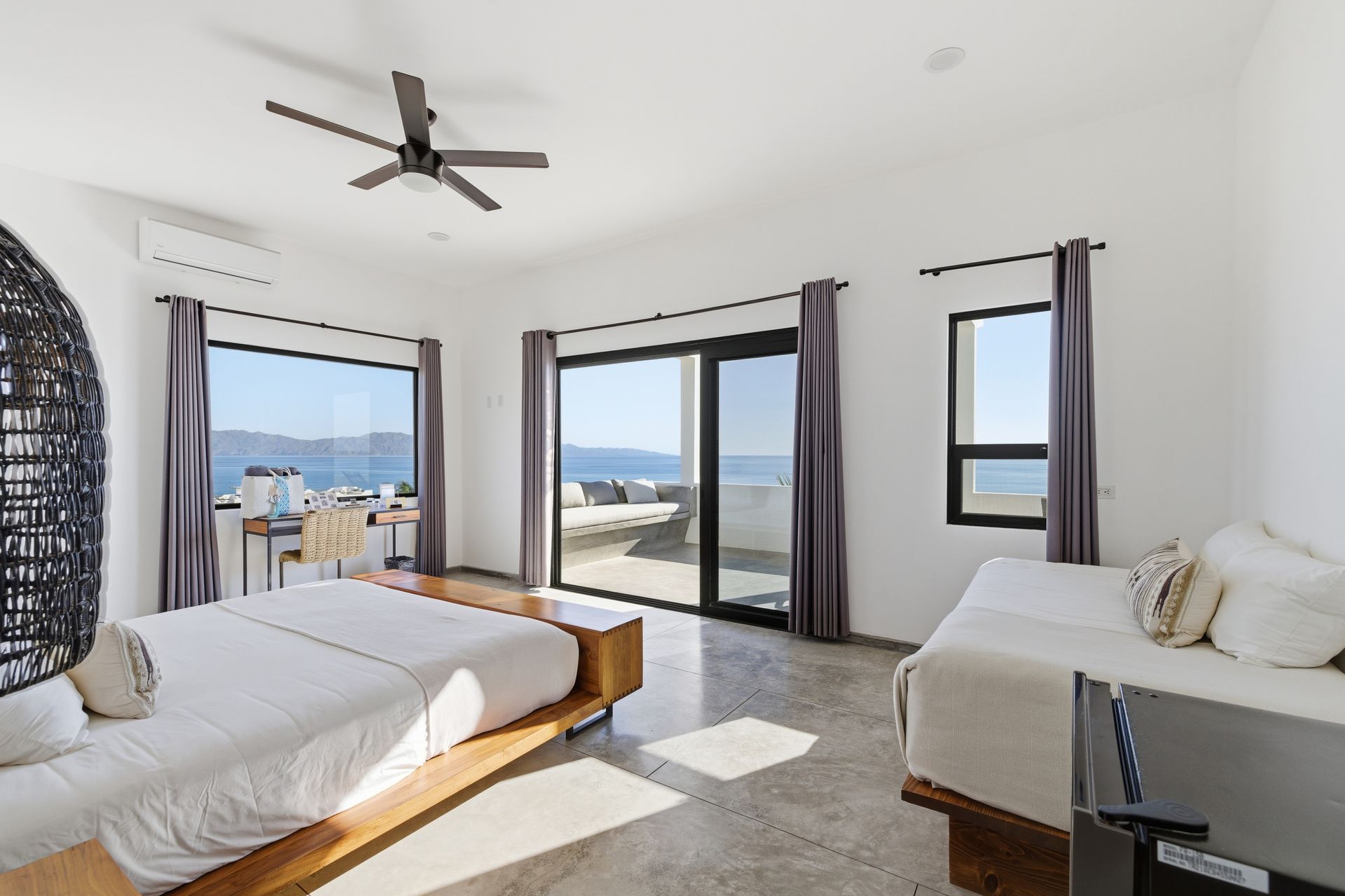 Bedroom with a bed, daybed, windows, ocean view, and ceiling fan.