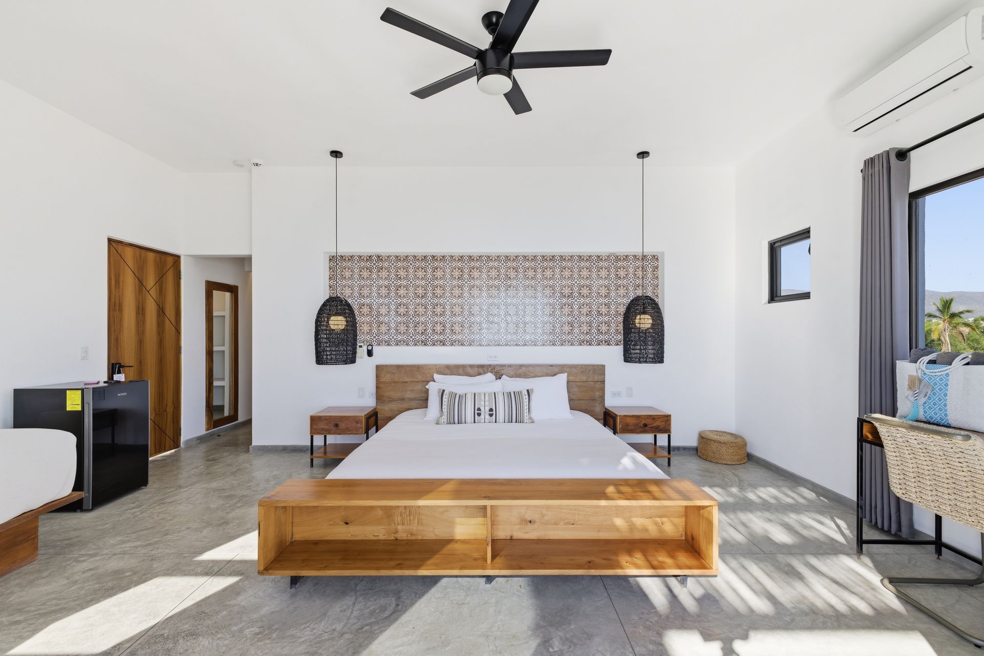 Bright bedroom with a king bed, wooden accents, and a large decorative headboard.
