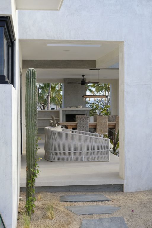 Modern outdoor patio with textured gray furniture, cactus, and stone pathway.