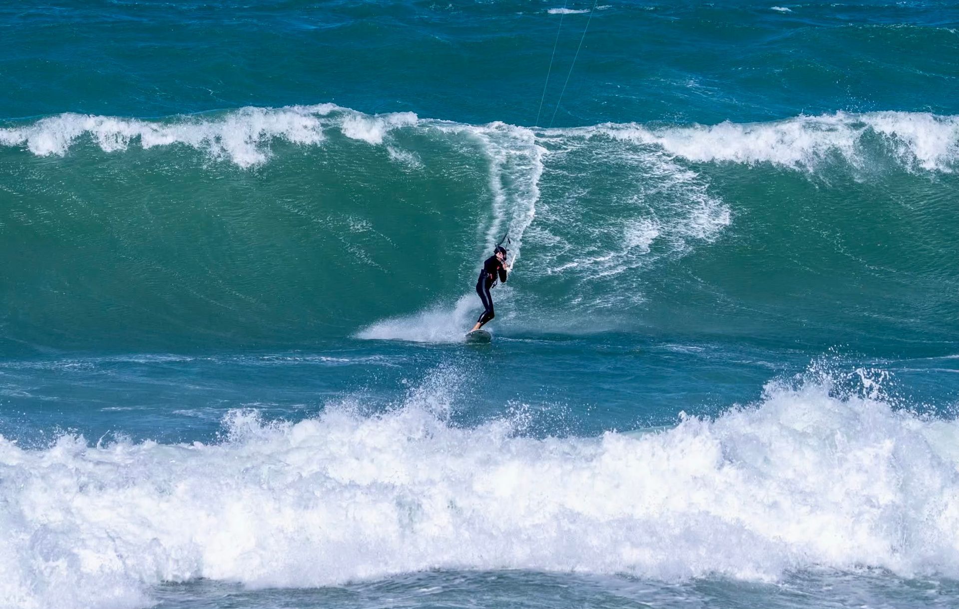 Surfer on a blue ocean wave, riding the face; white water and foamy crest.