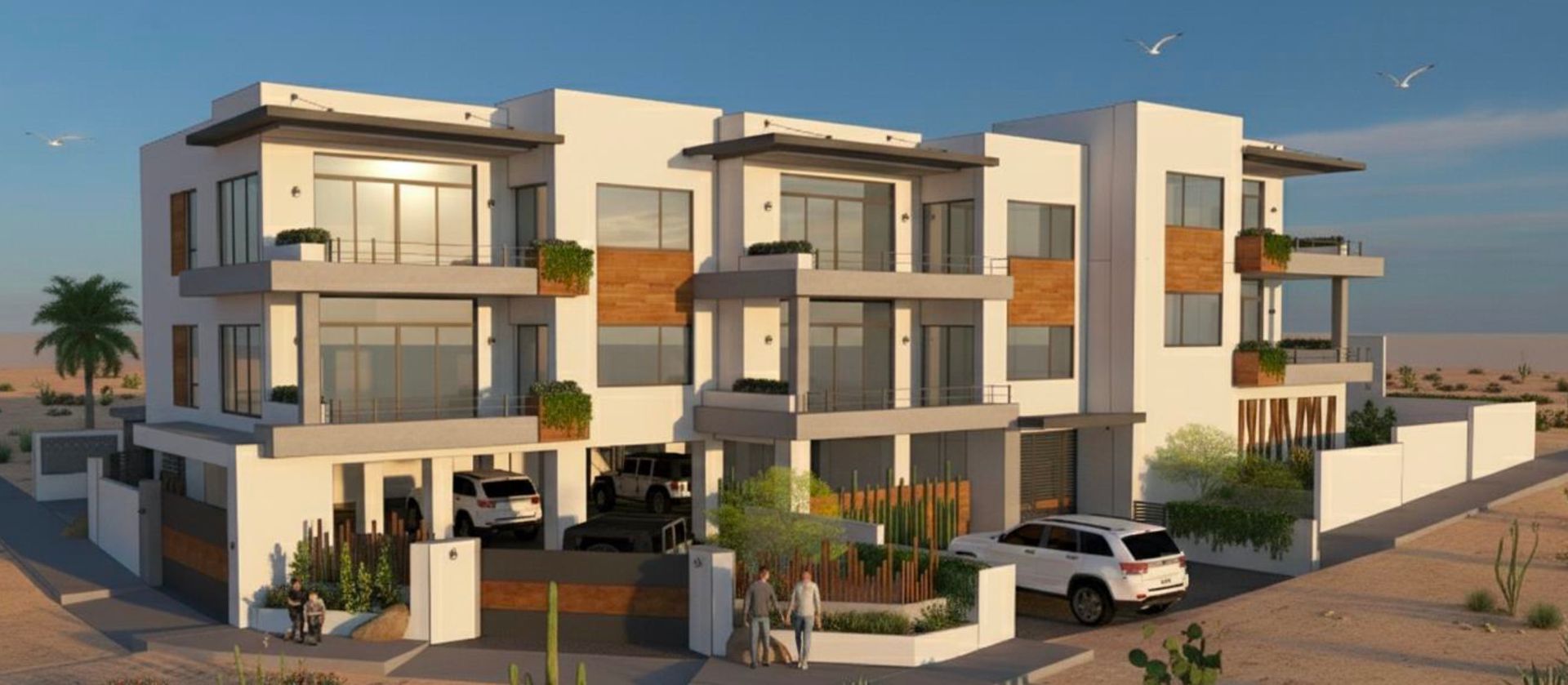 Modern multi-story white building with cars parked outside, set in a desert landscape.