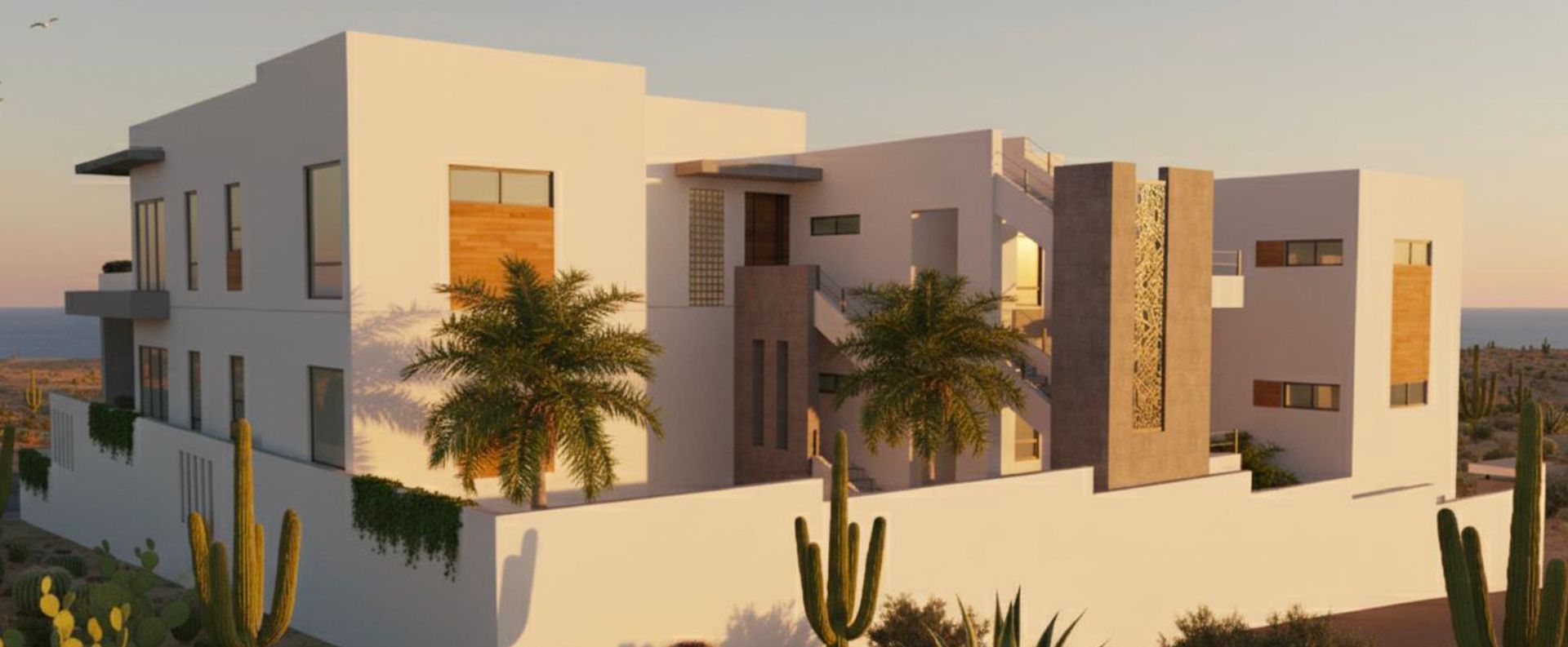 Modern white stucco house with geometric shapes, cacti, and ocean view.