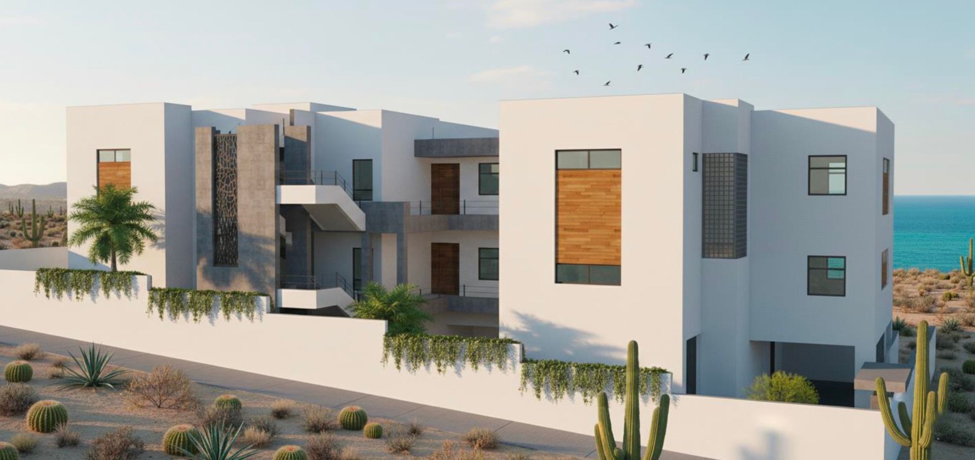 Modern white building complex in a desert landscape overlooking the ocean.