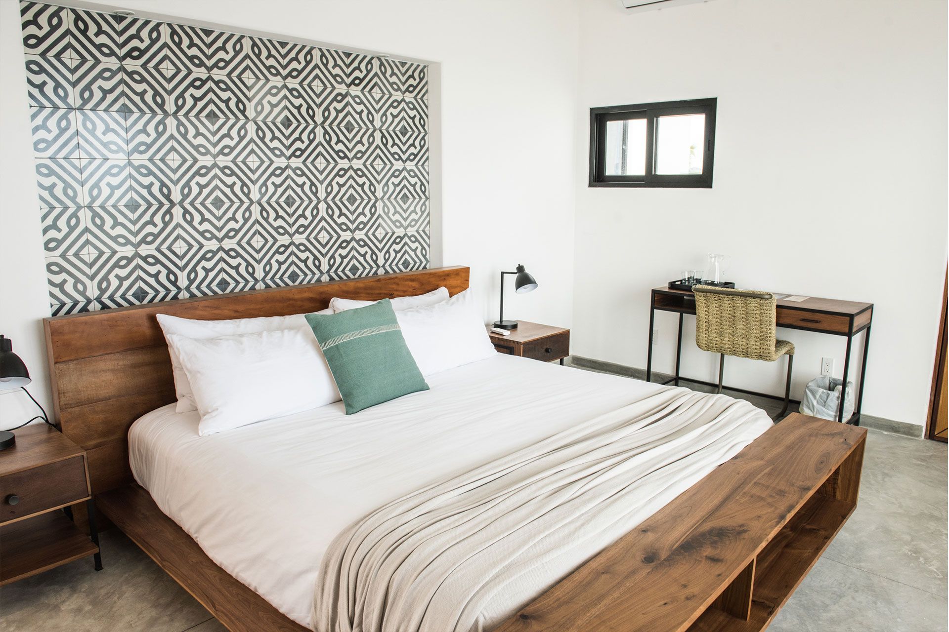 Bedroom with wooden bed frame, patterned headboard, desk, and bench.