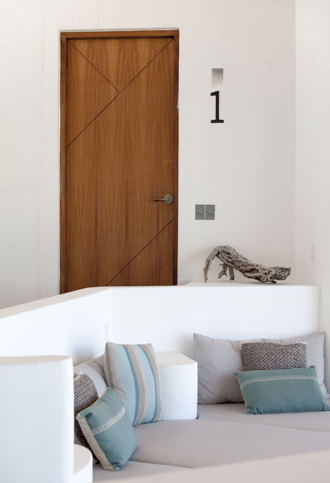 Wooden door with number 1, above built-in seating with pillows.