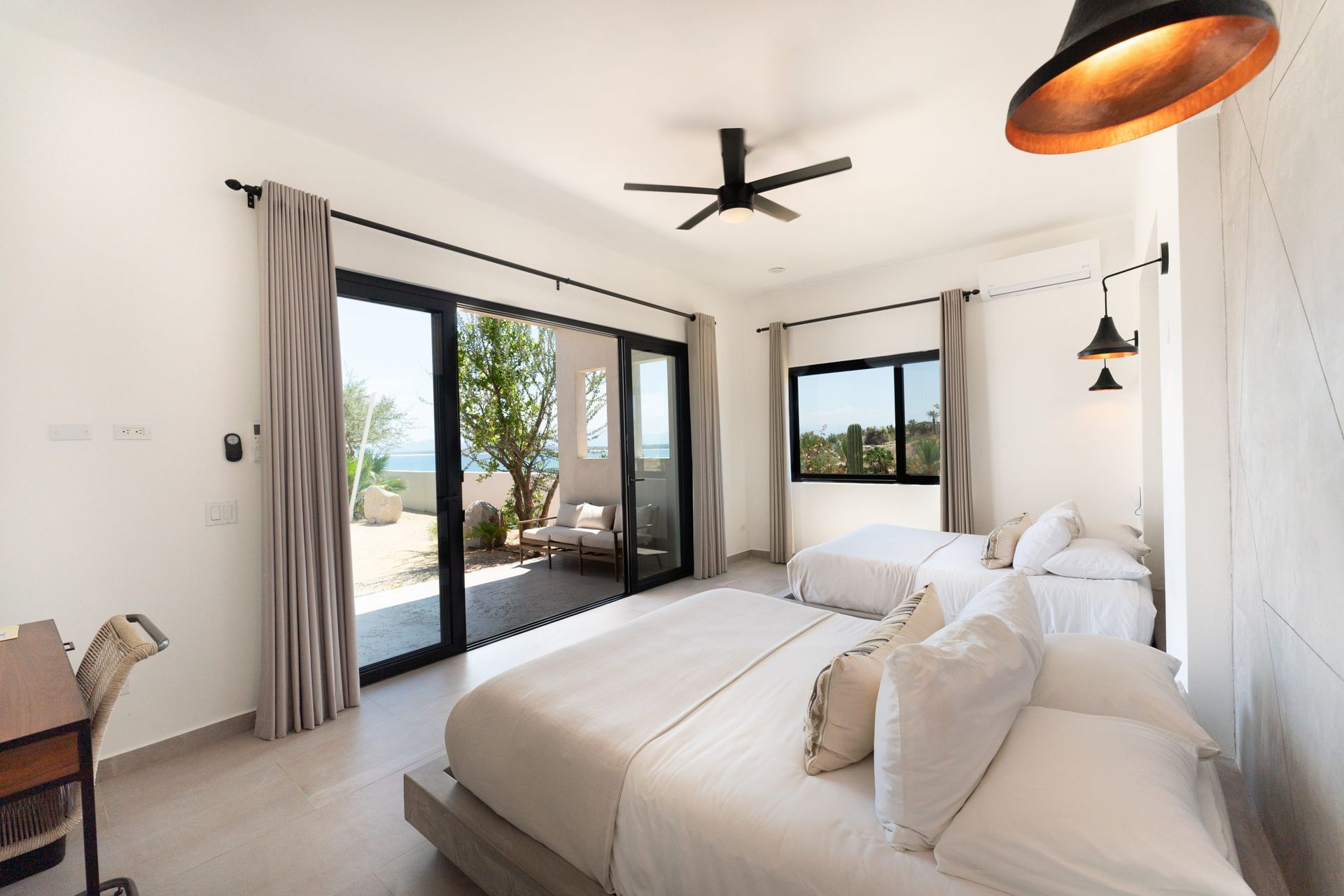 Bedroom with large bed, sliding door to patio, and smaller bed.