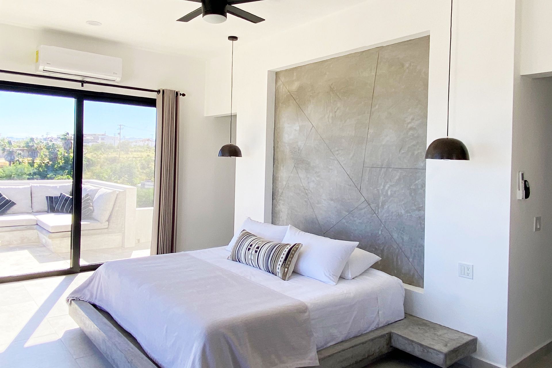 Modern bedroom with a bed, sliding glass door, and a terrace with a white sofa.