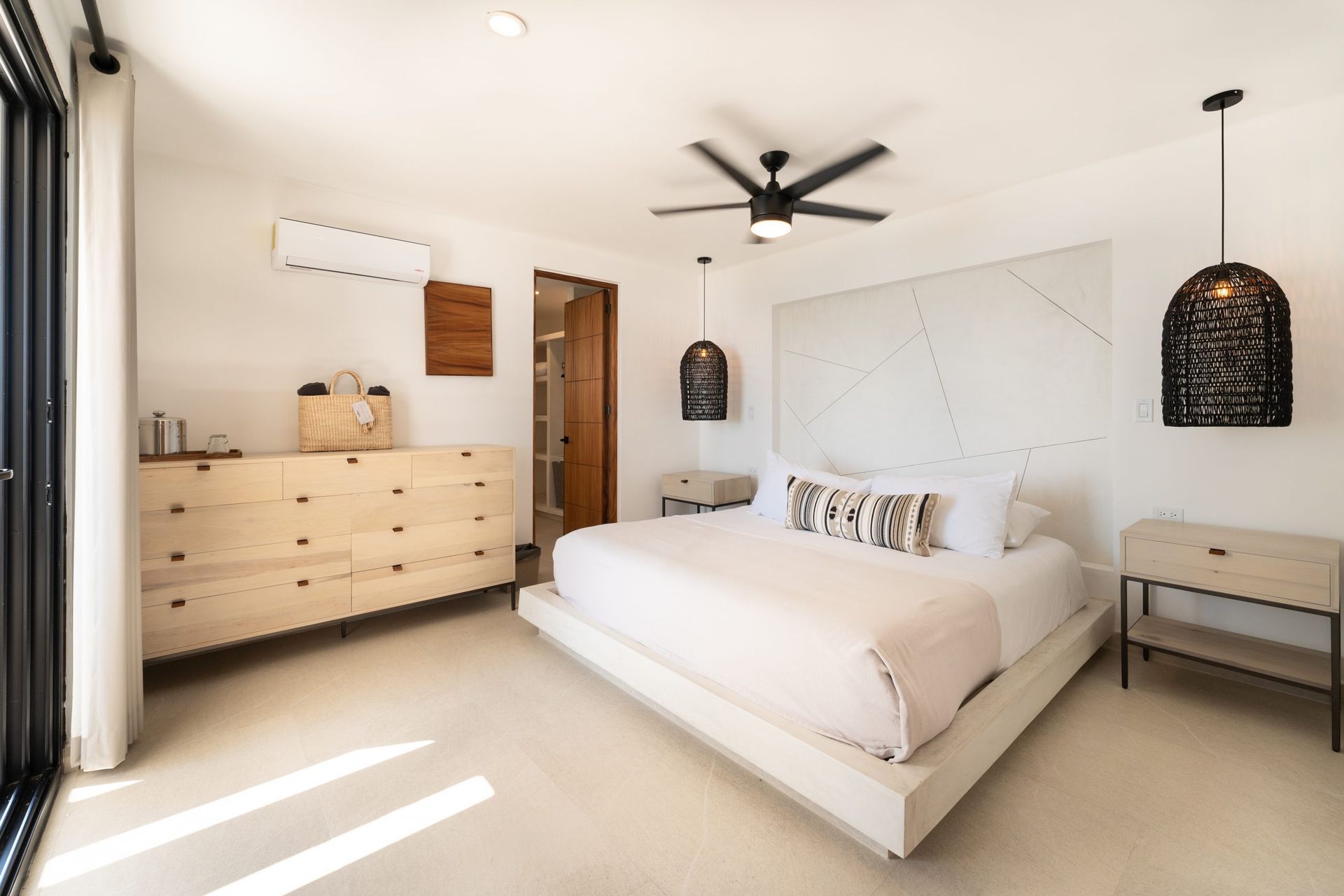 Bedroom with a light-colored bed frame, nightstands, dresser, and a large white headboard.