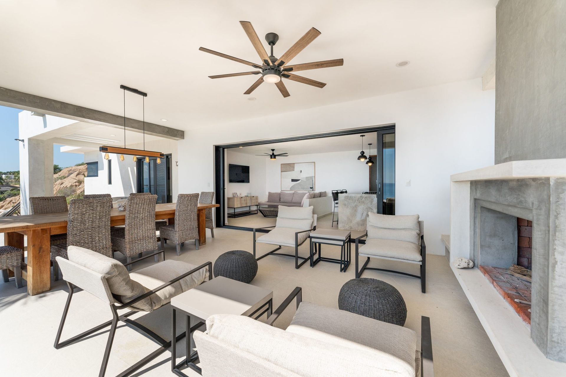 Outdoor patio with dining and lounge areas, fireplace, and ceiling fans.