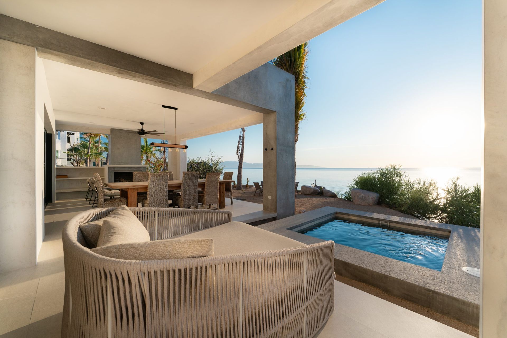 Patio with lounge chair, small pool, and ocean view on a sunny day.
